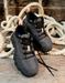Pair of black and gray sneakers with pink accents on a wooden surface with ropes in the background