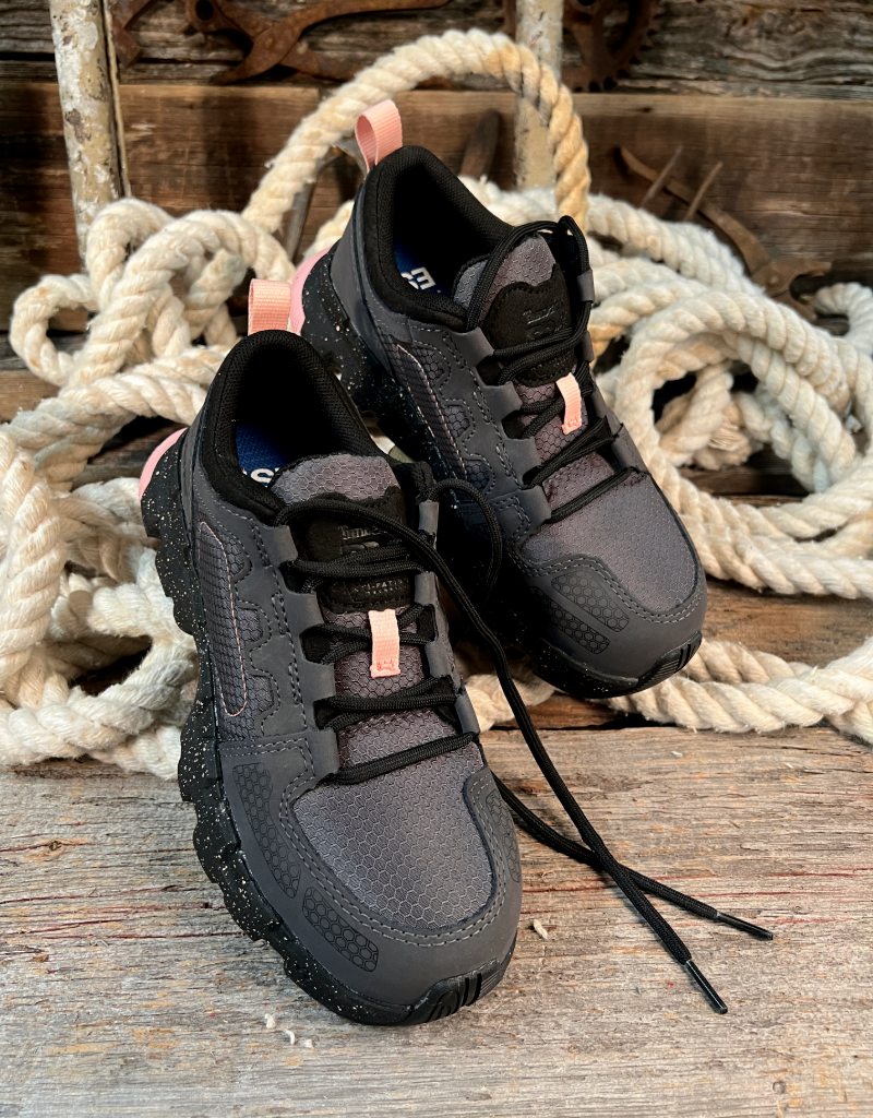 Pair of black and gray sneakers with pink accents on a wooden surface with ropes in the background