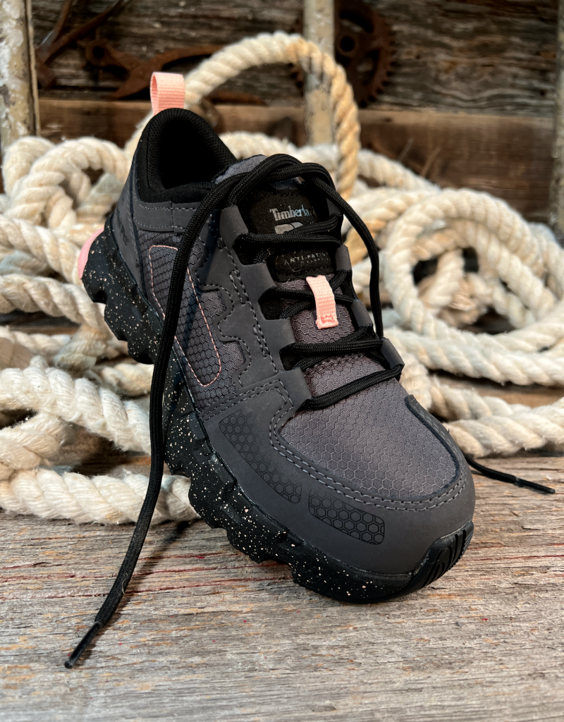 Black sneaker with pink accents on a wooden surface with ropes in the background