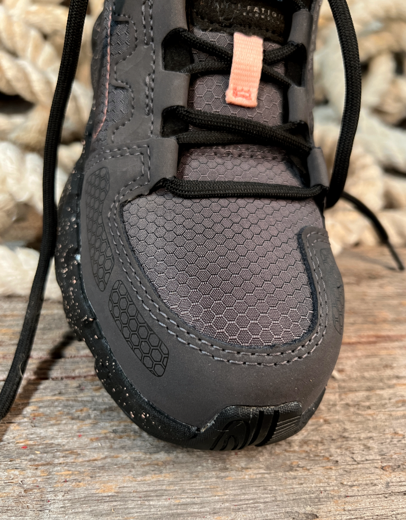 Close-up of a dark grey shoe toe  on a wooden surface