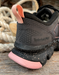 Closeup of a grey tennis sneaker heel with a black and pink sole- featuring a timberland PRO composite safety toe label on a wooden background