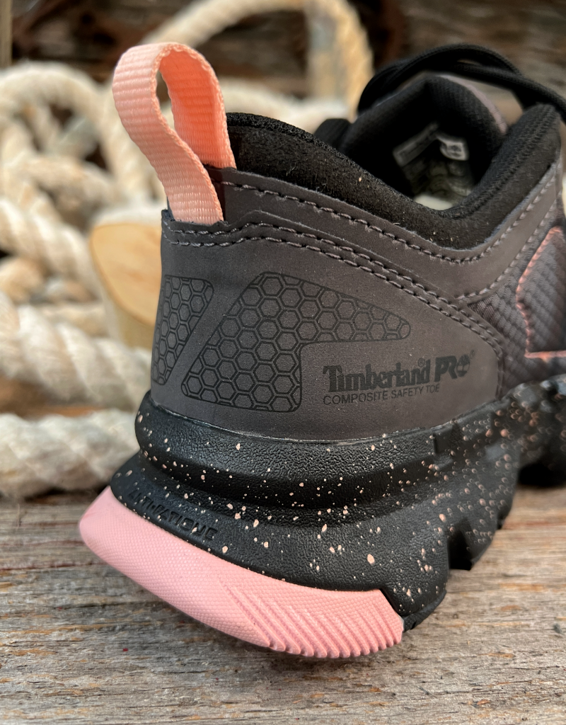 Closeup of a grey tennis sneaker heel with a black and pink sole- featuring a timberland PRO composite safety toe label on a wooden background