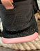Close-up of a grey sneaker with a black and pink sole on a wooden floor.