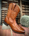 Brown cowboy boot on a wooden surface with a rustic background