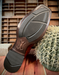 Close-up of Ariat Bantamweight boot sole with tread pattern on a wooden surface with a cactus.