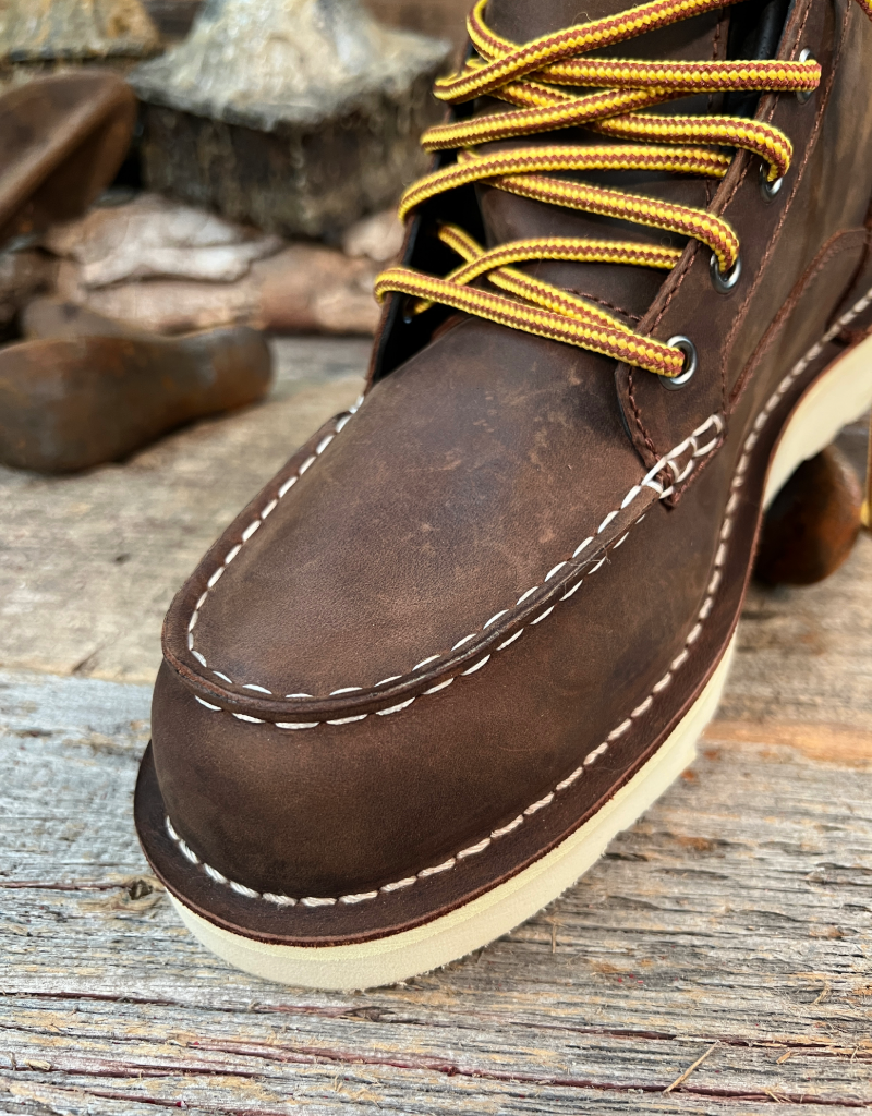 Close-up of a brown leather boot with yellow laces on a wooden surface.