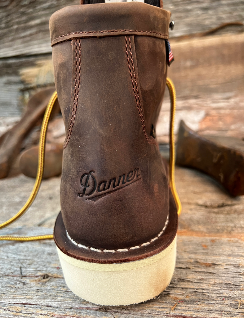 Brown leather boot with 'Danner' branding on a wooden surface