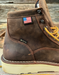 Brown leather boot with American flag patch and GORE-TEX label on a wooden surface