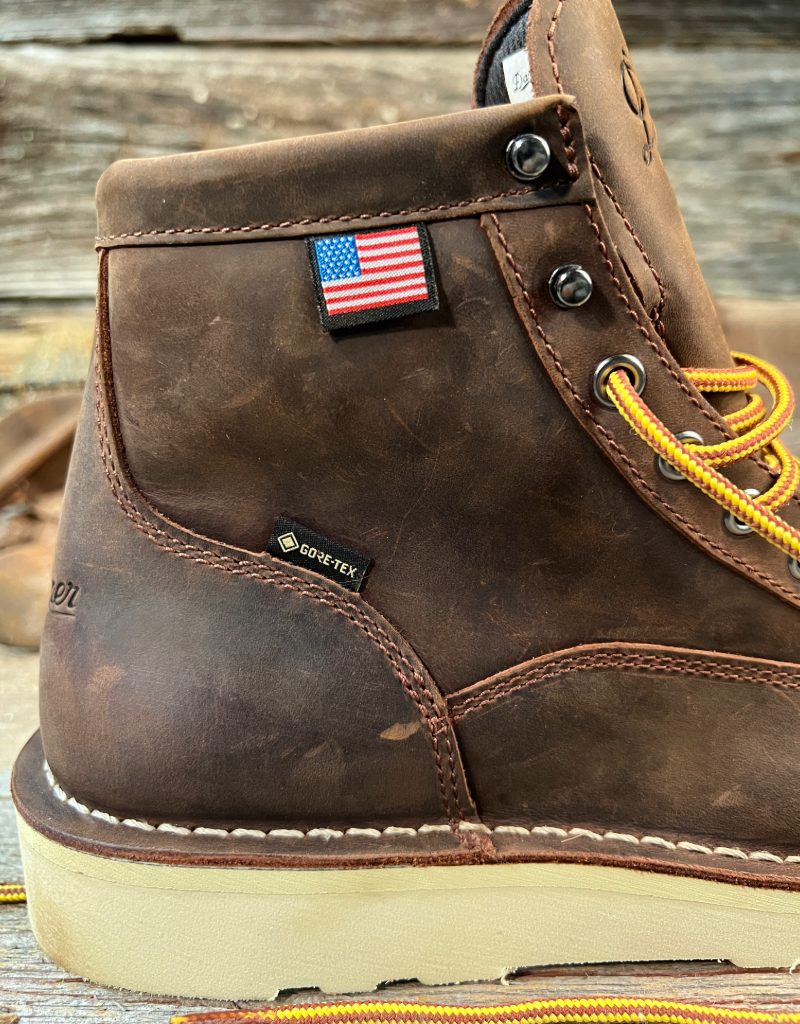 Brown leather boot with American flag patch and GORE-TEX label on a wooden surface