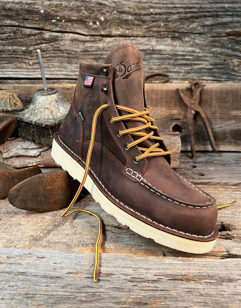Brown leather boot with yellow laces on a wooden background
