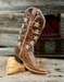 Brown cowboy boot with star patterns on a wooden surface