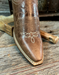 Brown leather boot with decorative stitching on a wooden surface