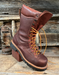 Brown leather boot with orange laces on a wooden background