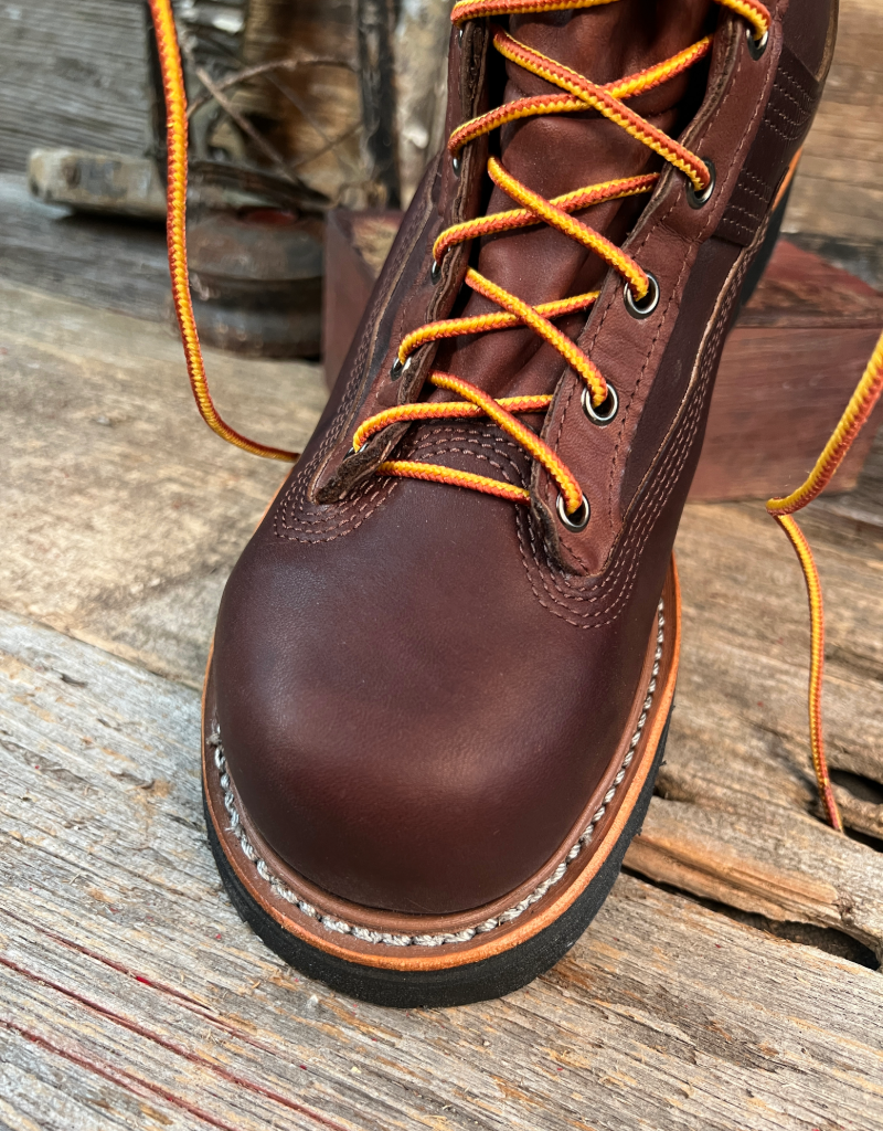 Brown leather boot with orange laces on a wooden surface