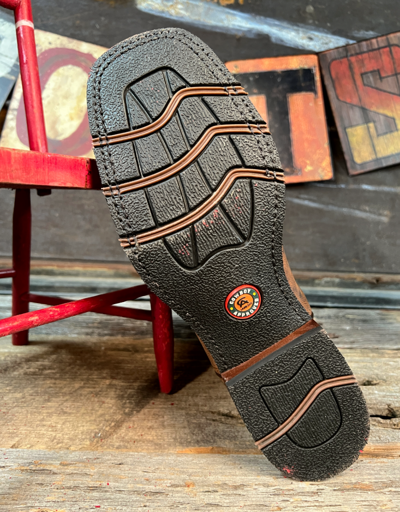 Close-up of a black and brown boot sole with a brand logo on a rustic wooden surface.