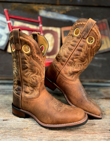 Pair of brown cowboy boots with intricate designs on a wooden surface.