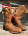 Pair of brown cowboy boots with intricate designs on a wooden surface.