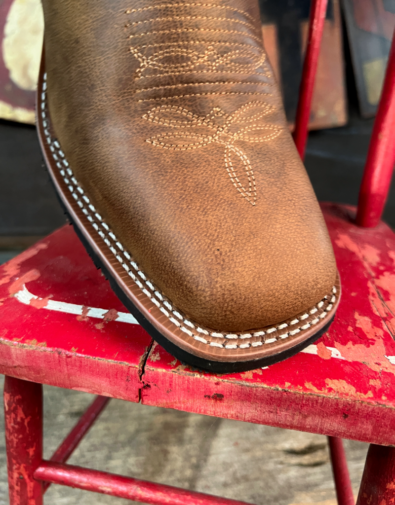 Brown leather boot with intricate stitching on a red chair