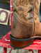 Brown leather boot with intricate stitching on a red chair