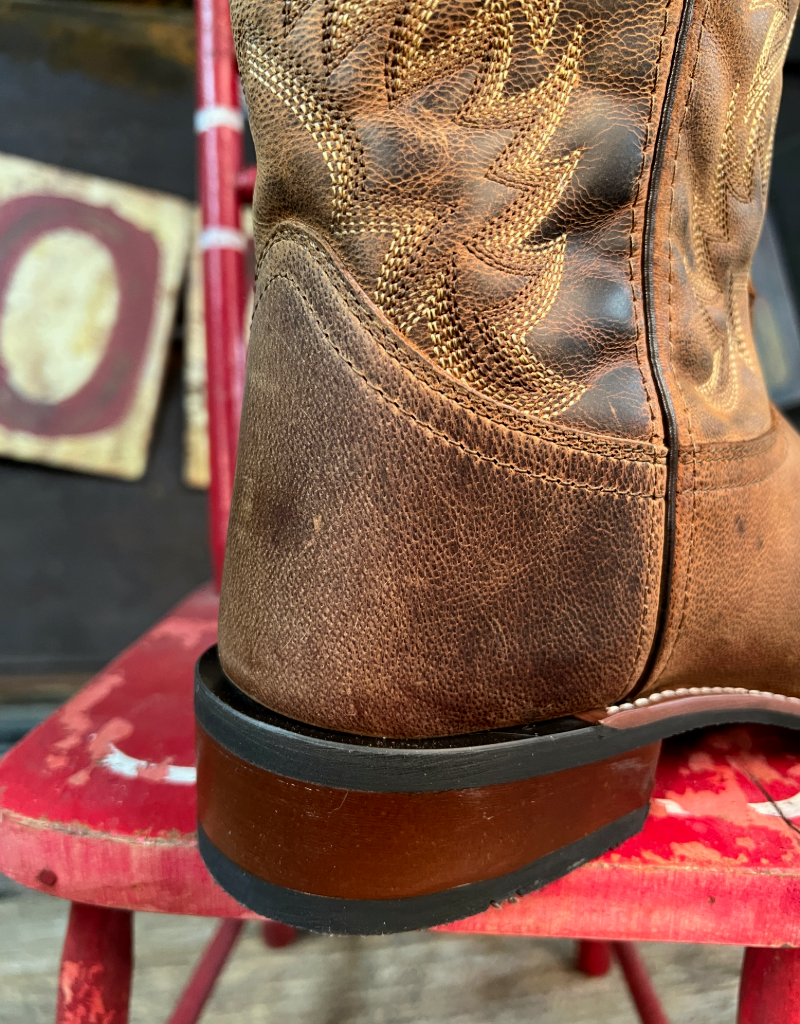 Brown leather boot with intricate stitching on a red chair