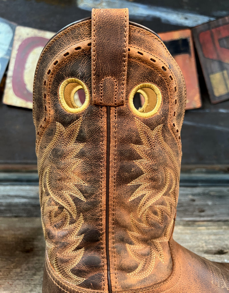 Close-up of a brown leather cowboy boot with intricate stitching on a wooden surface.