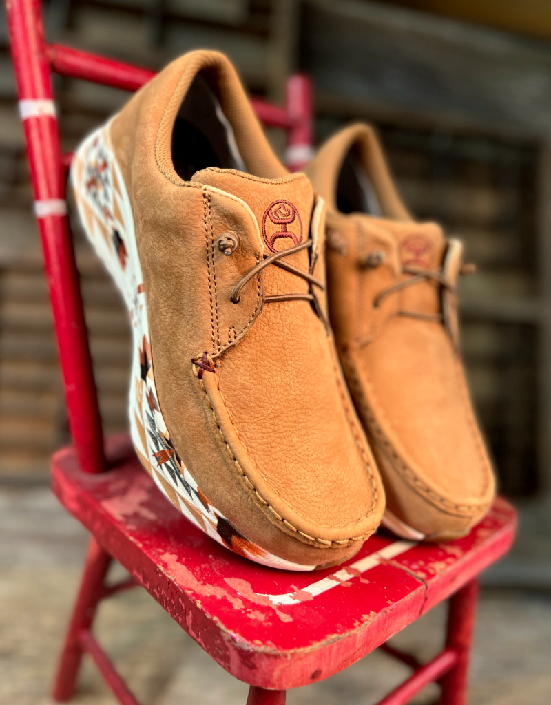 Pair of tan leather shoes with colorful soles on a red chair.