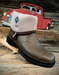 Brown rubber boot with beige lining on a wooden surface, vintage red truck in the background