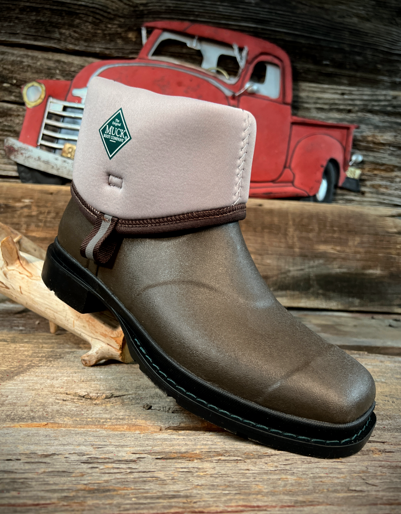 Brown rubber boot with beige lining on a wooden surface, vintage red truck in the background