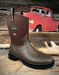 Brown Muck boot on a wooden surface with a red vintage truck in the background
