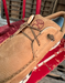 Close-up of a brown leather shoe with a Hooey brand logo and elastic laces on a red surface.