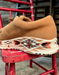Brown leather shoe with an aztec patterned sole on a red chair.