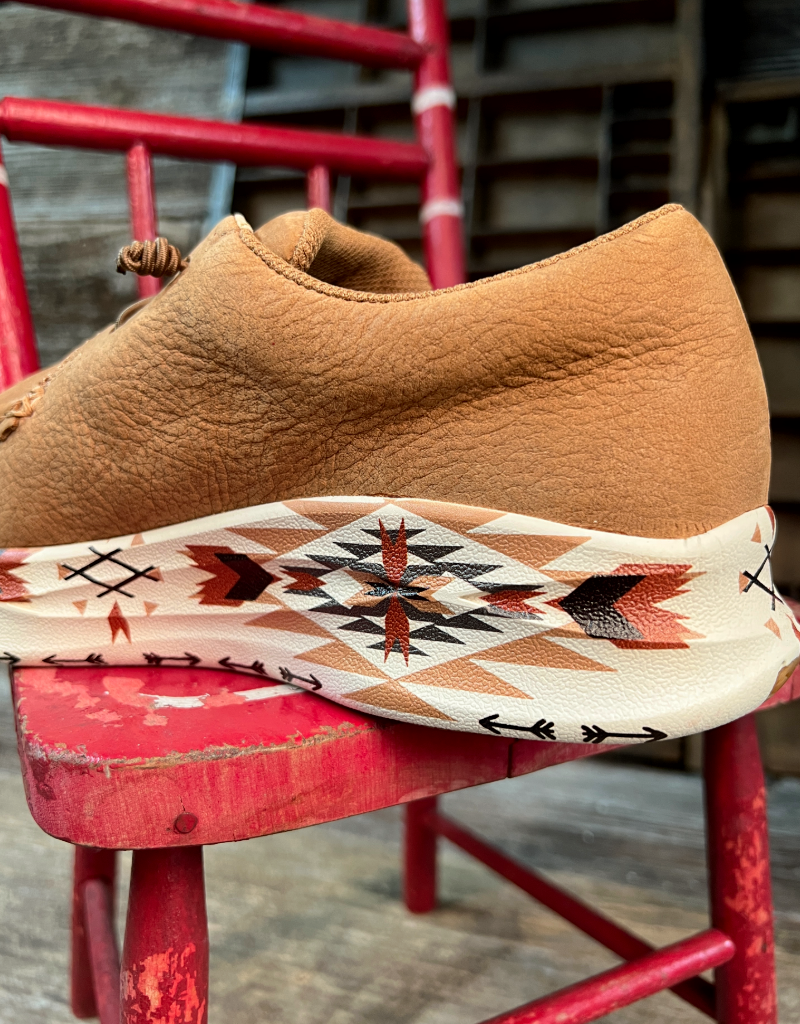Brown leather shoe with an aztec patterned sole on a red chair.