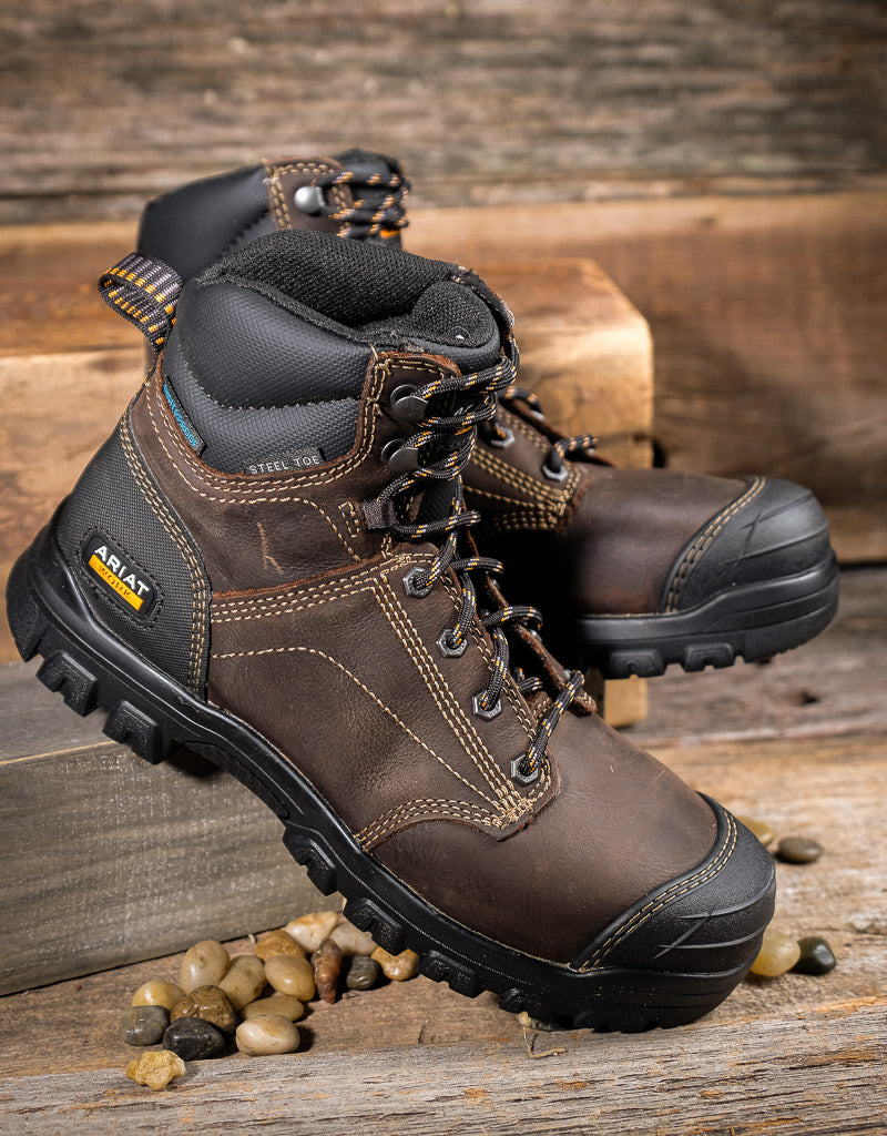 Brown Ariat boots with black soles on a wooden surface