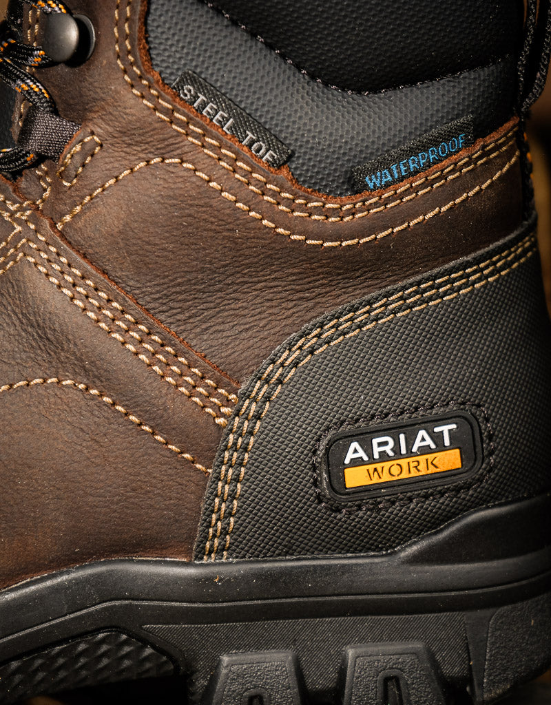 Close-up of a brown work boot with Ariat branding, featuring steel toe and waterproof labels.