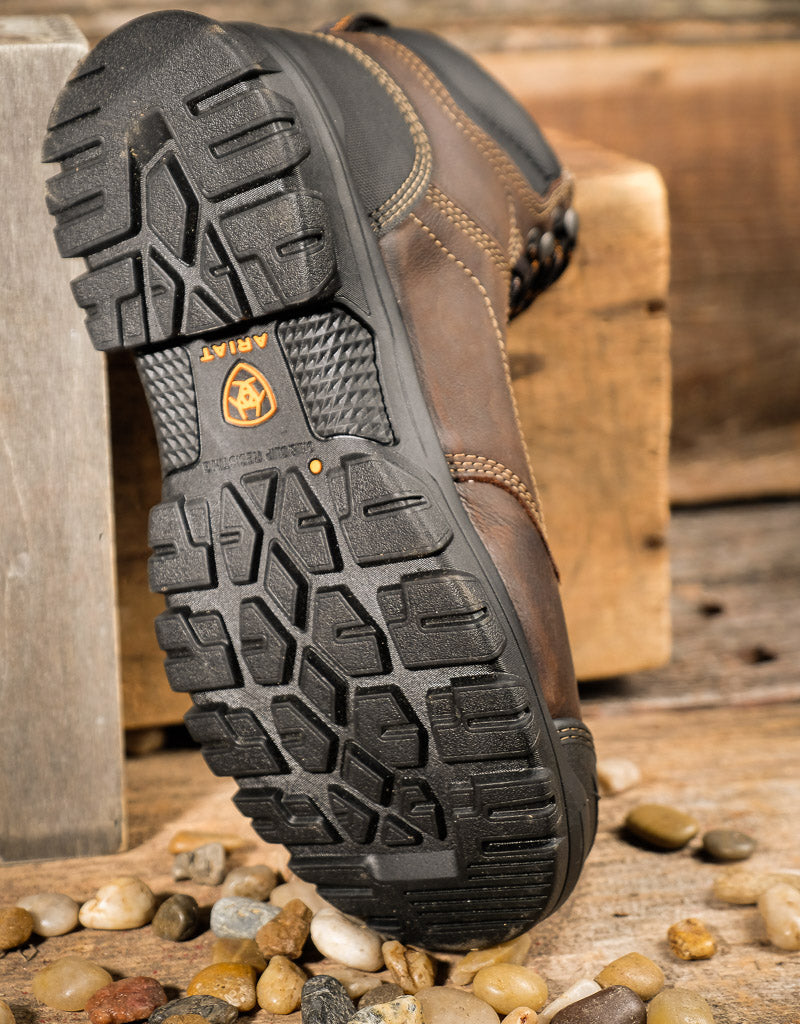 Close-up of a brown boot  sole with a textured sole on a wooden surface with pebbles.