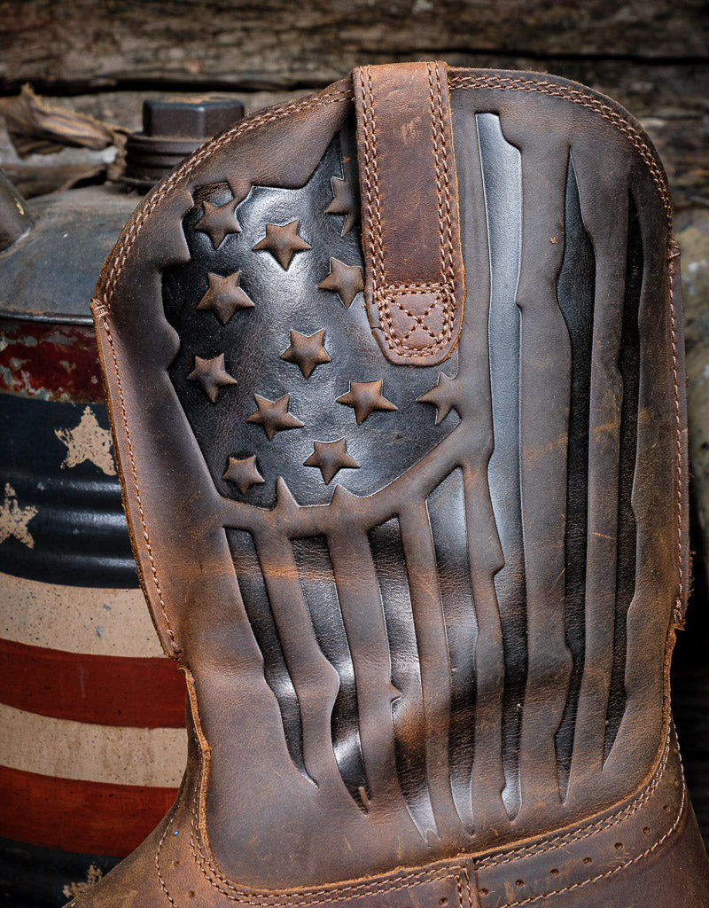 Close up of the star and stripe tooling on the leather shaf of this Ariat western boot. With a blurred wooden background
