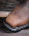 Close up on square toe brown western boot toe with a blurred wooden background