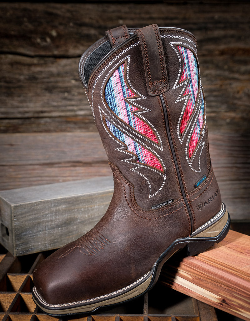 Brown cowgirl boot with colorful vent panels on a wooden surface
