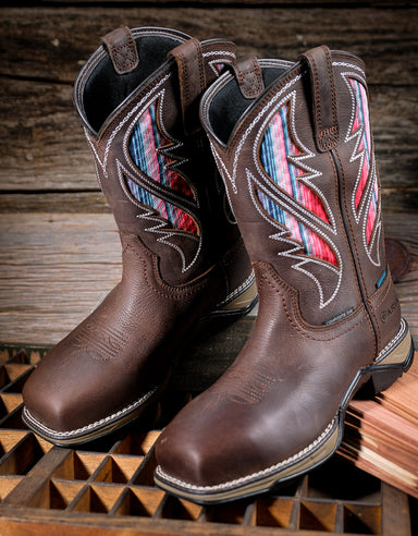 Pair of brown cowgirl boots with colorful vent panels on a wooden surface