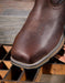 Brown leather boot with detailed stitching on a wooden surface