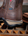 Brown leather boot with Ariat logo on a wooden surface