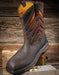 Brown work boot with orange vent panels on a wooden background