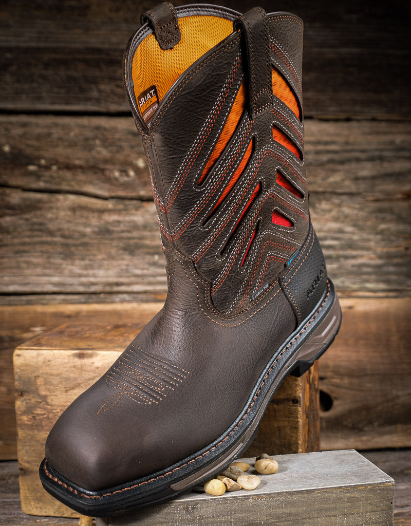 Brown work boot with orange vent panels on a wooden background