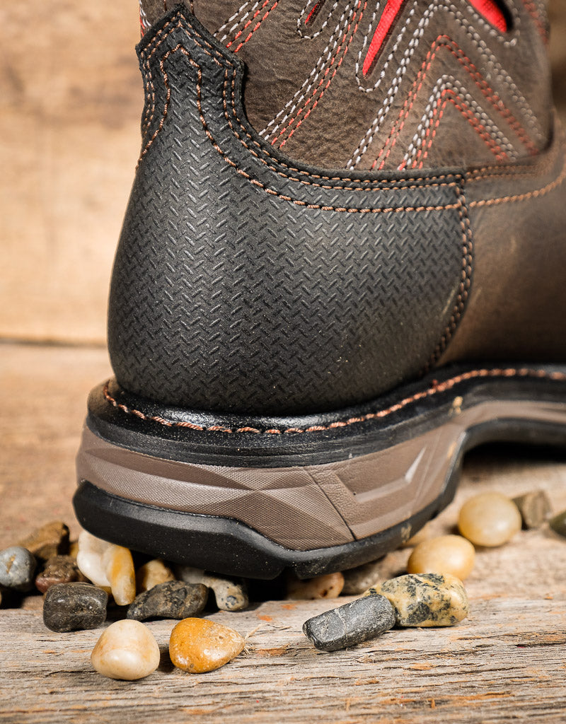 Close-up of a brown leather boot heel  on a wooden surface with stones.