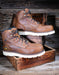 Brown work boots with white soles on a wooden crate against a rustic wooden background