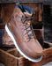 Brown leather boot with white sole on a wooden background