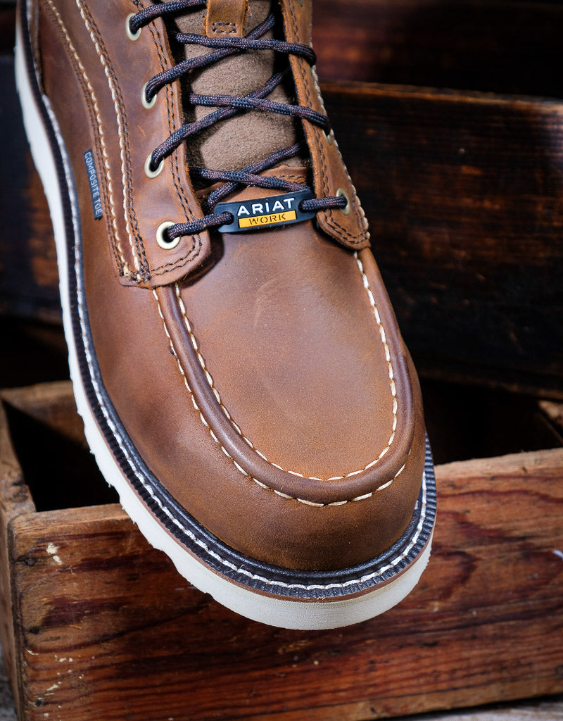 Brown leather boot with laces on a wooden surface, featuring the Ariat logo.