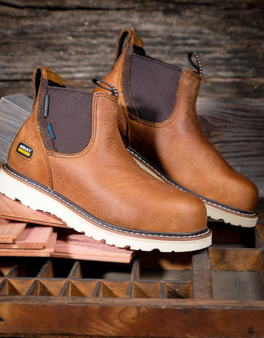 Brown leather chelsea style boots with white soles on a wooden surface