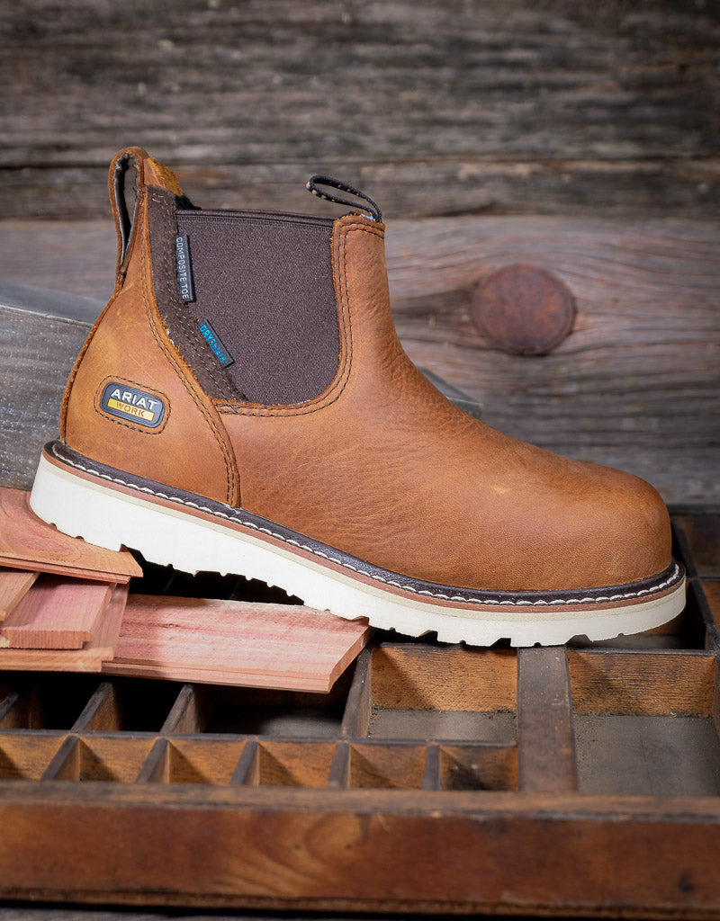 Brown work boot with white sole on a wooden surface