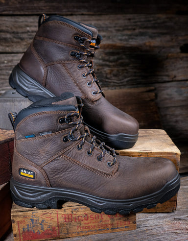 Brown work boots on a wooden pallet with a rustic background